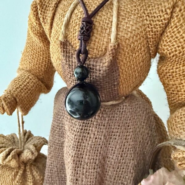Pendentif Protection Ultime – Obsidienne Œil Céleste en sphère. Dimension de la pierre : 1.5 cm. Livré avec cordon en coton de couleur brun. Boutique de lithothérapie La Porte des Secrets